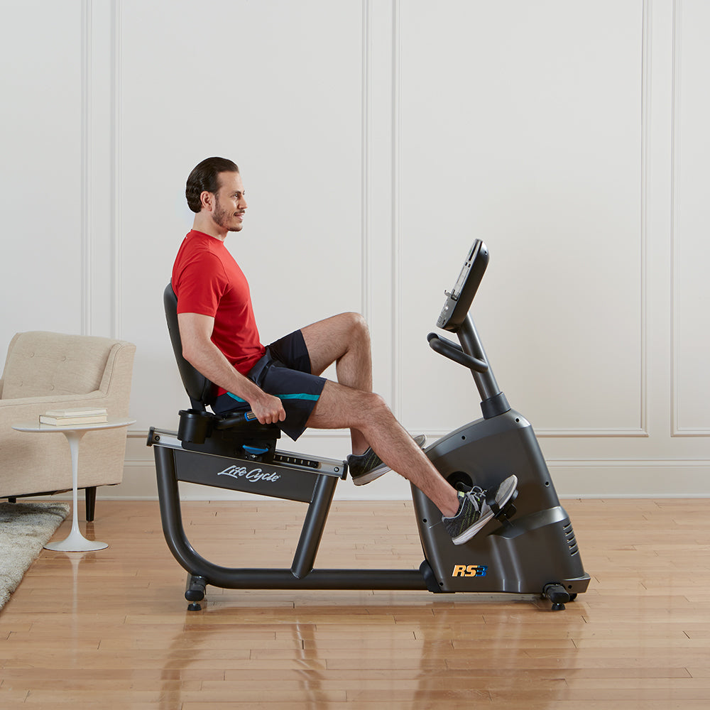 Hombre pedaleando en la bicicleta reclinada RS3 Life Fitness, vista lateral